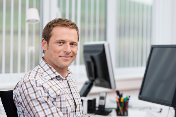 Man sitting at desk in front of computers.